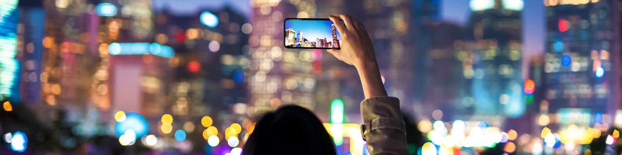 都会の夜空の写真を撮影している人物