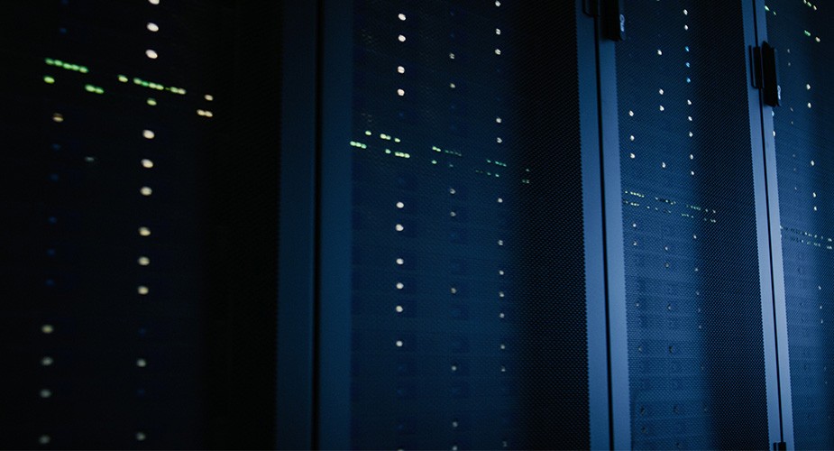 暗いデータセンターに並ぶ光に照らされたサーバー群
