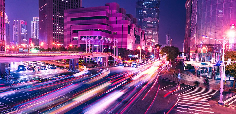 夜の賑やかな街。車のライトの筋
